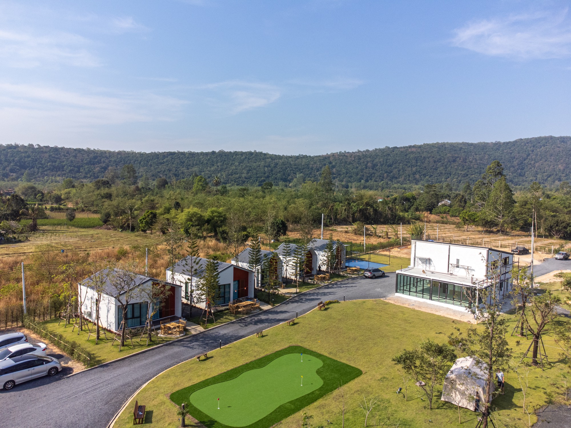 Aerial view of Myrrh Resort grounds with villas, the glass restaurant, mini putting green, and mountains